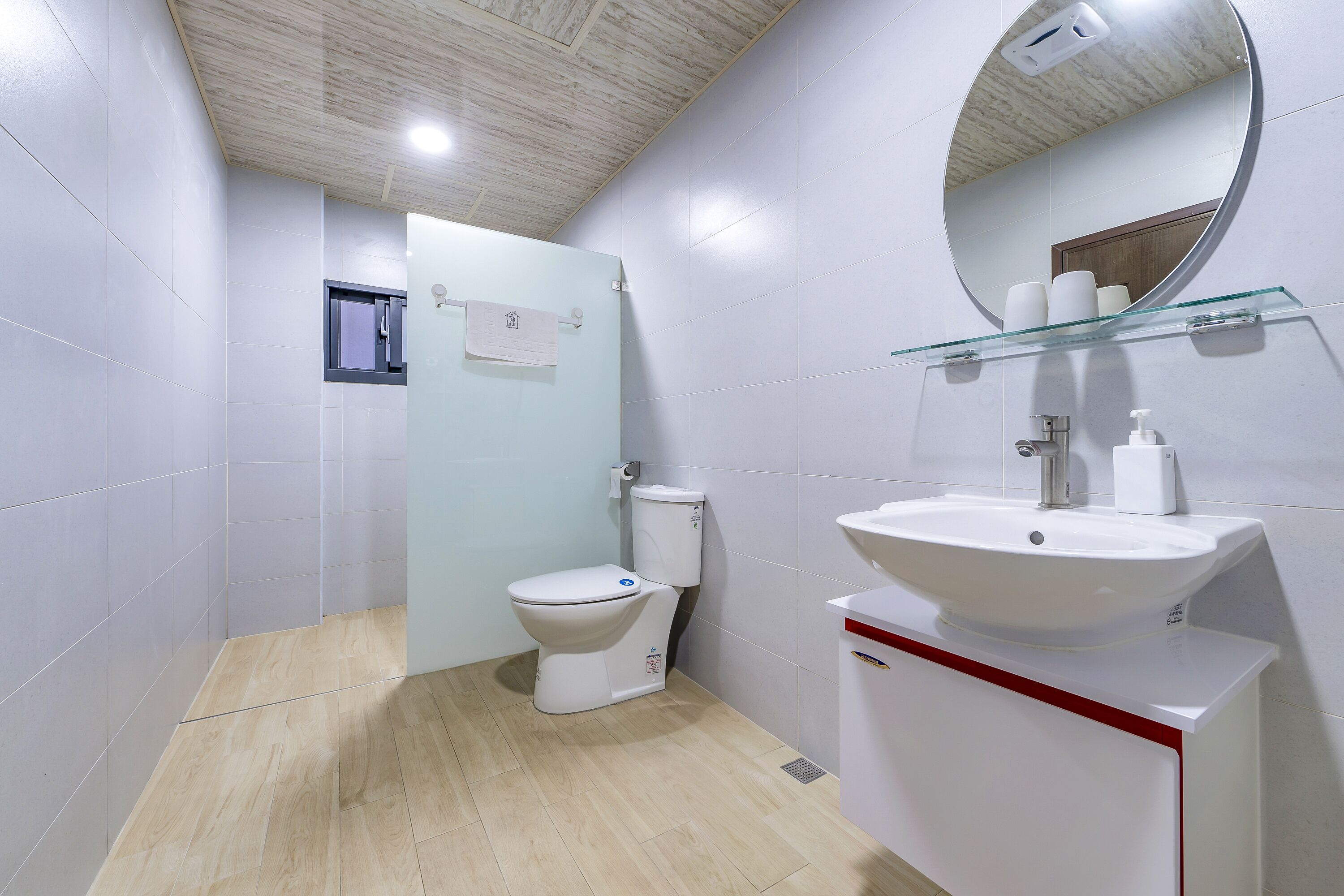 A modern bathroom with a toilet, sink, and glass shelf.