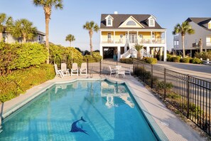 A swimming pool with a dolphin decal, surrounded by white lounge chairs and a fence, with a house in the background. - Marlin View: Oceanfront w/ Pool, Walk to Dining (Garden City)
