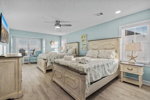 A bedroom with two beds, a ceiling fan, and a view of the ocean through the windows. - Marlin View: Oceanfront w/ Pool, Walk to Dining (Garden City)