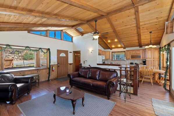 A spacious living room with a leather sofa, wooden coffee table, and a dining area with a wooden table and chairs.