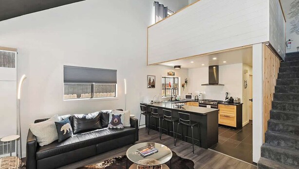 Un apartamento moderno con sala de estar, cocina y escalera.