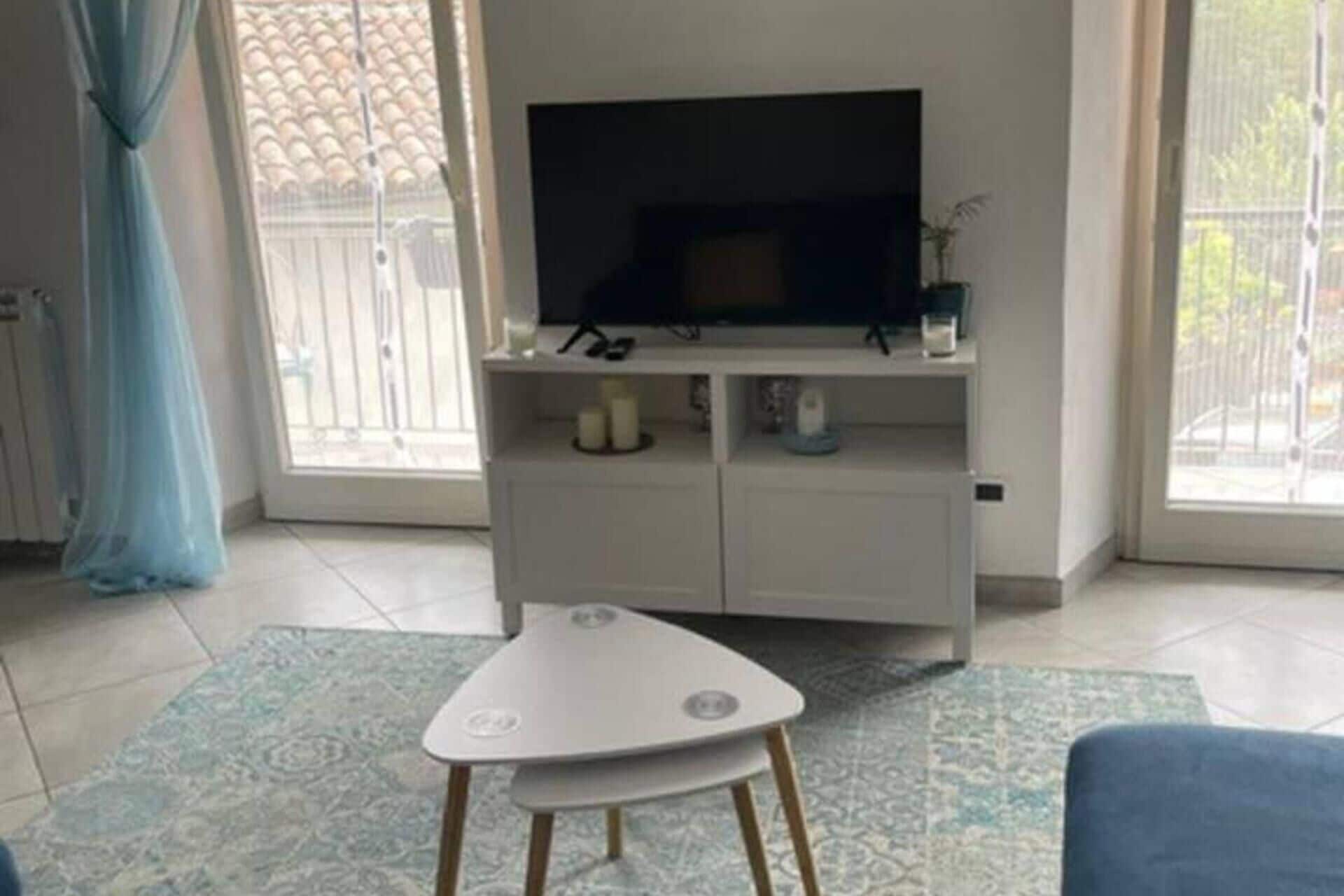 Un soggiorno con una TV su un mobile bianco, un tavolino e un tappeto decorato.