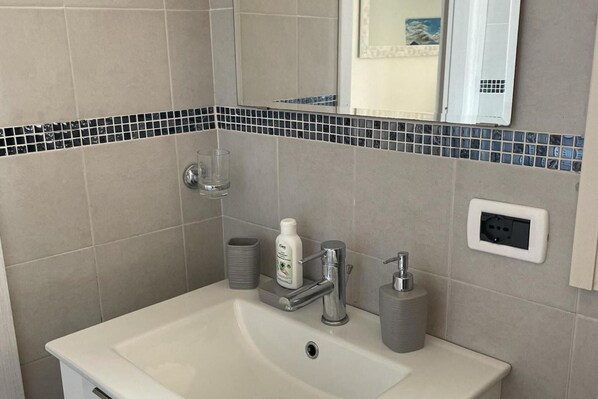 A bathroom with a sink, mirror, and a small glass container. - Beautiful Retreat in the Heart of Piedmont Wine Country (Strevi)
