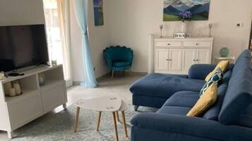 A living room with a sofa, a television, a cabinet, and a painting on the wall.