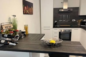 Une cuisine moderne avec un meuble à vin, un bol de citrons et un tableau accroché au mur.