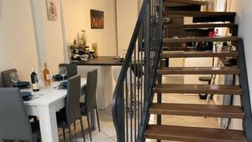 A staircase leading to a dining area with a table set for two, chairs, and a bottle of wine.