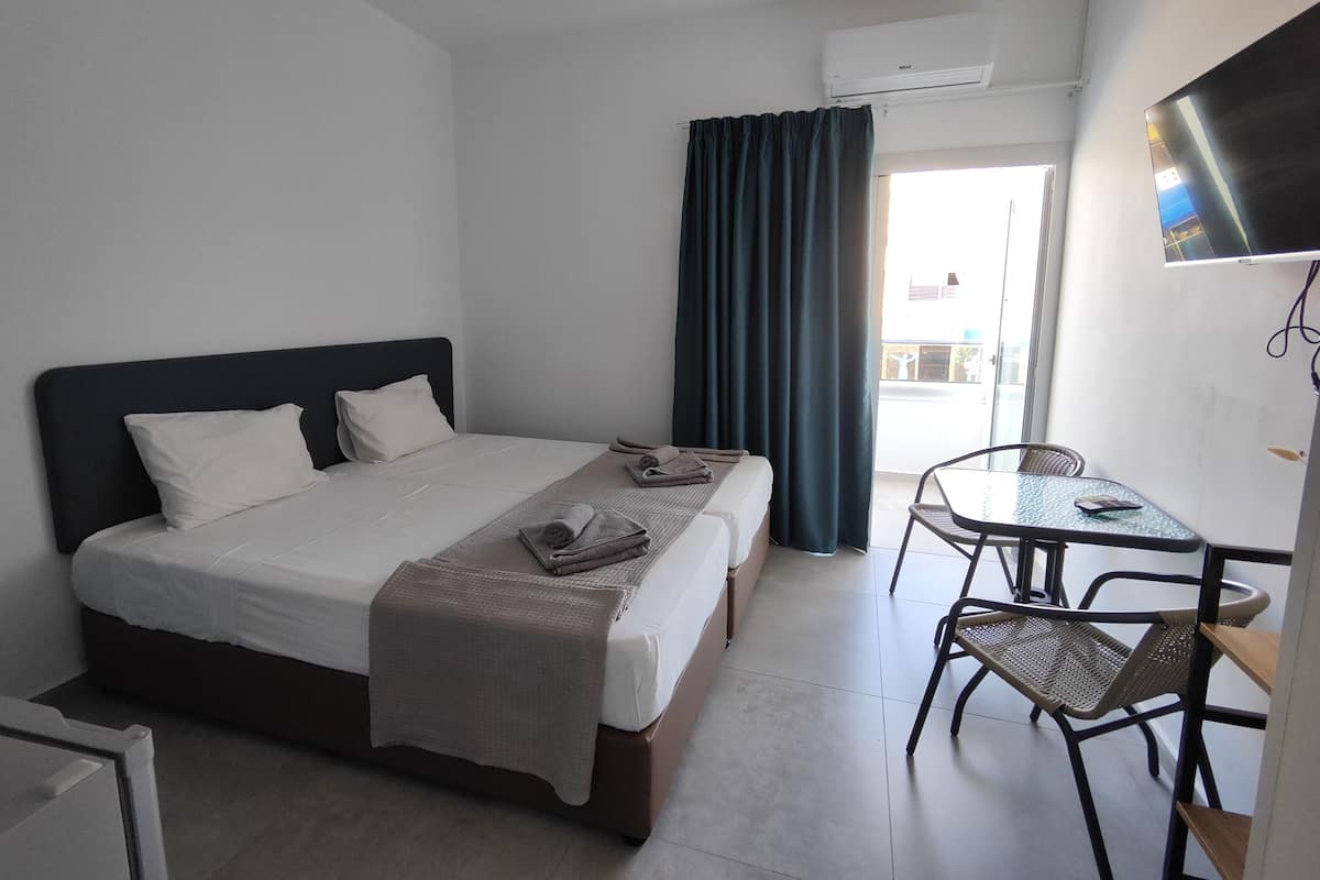 A hotel room with a bed, a desk, a chair, and a TV.