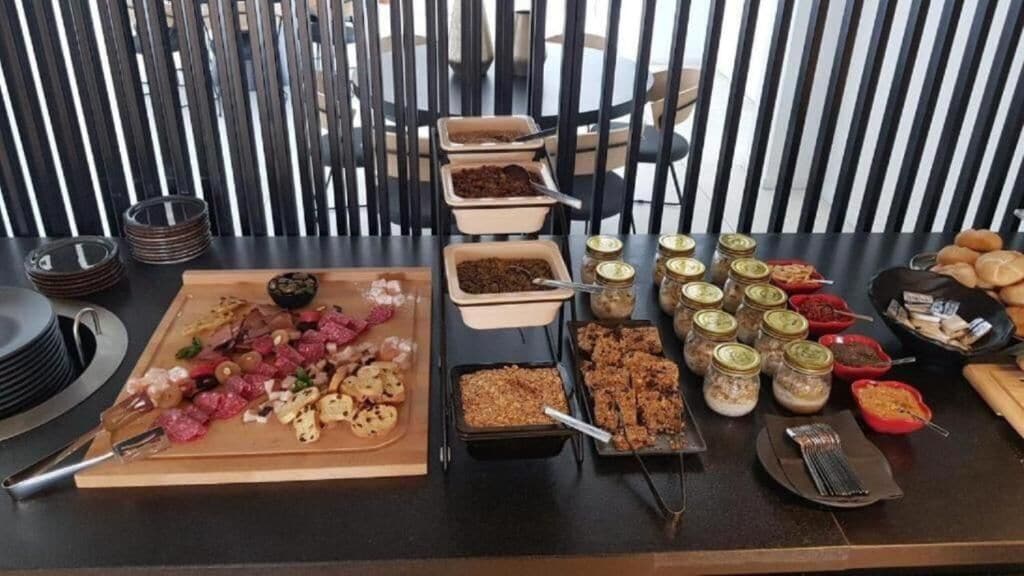 A buffet table with various food items, including meats, salads, and desserts, arranged on a table with a striped background.