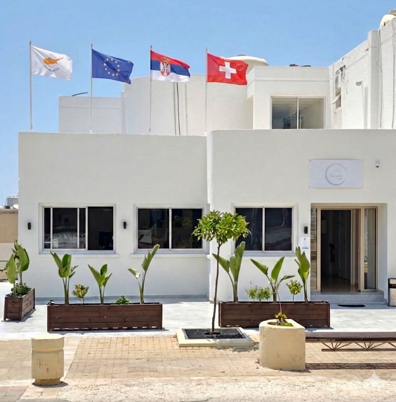 A building with multiple flags, including the European Union flag, and a sign indicating a medical facility.