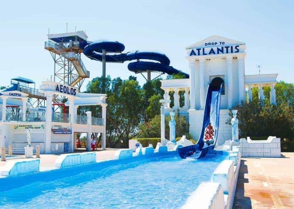 A water park with a large water slide labeled "Drop to Atlantis" and a pool area.