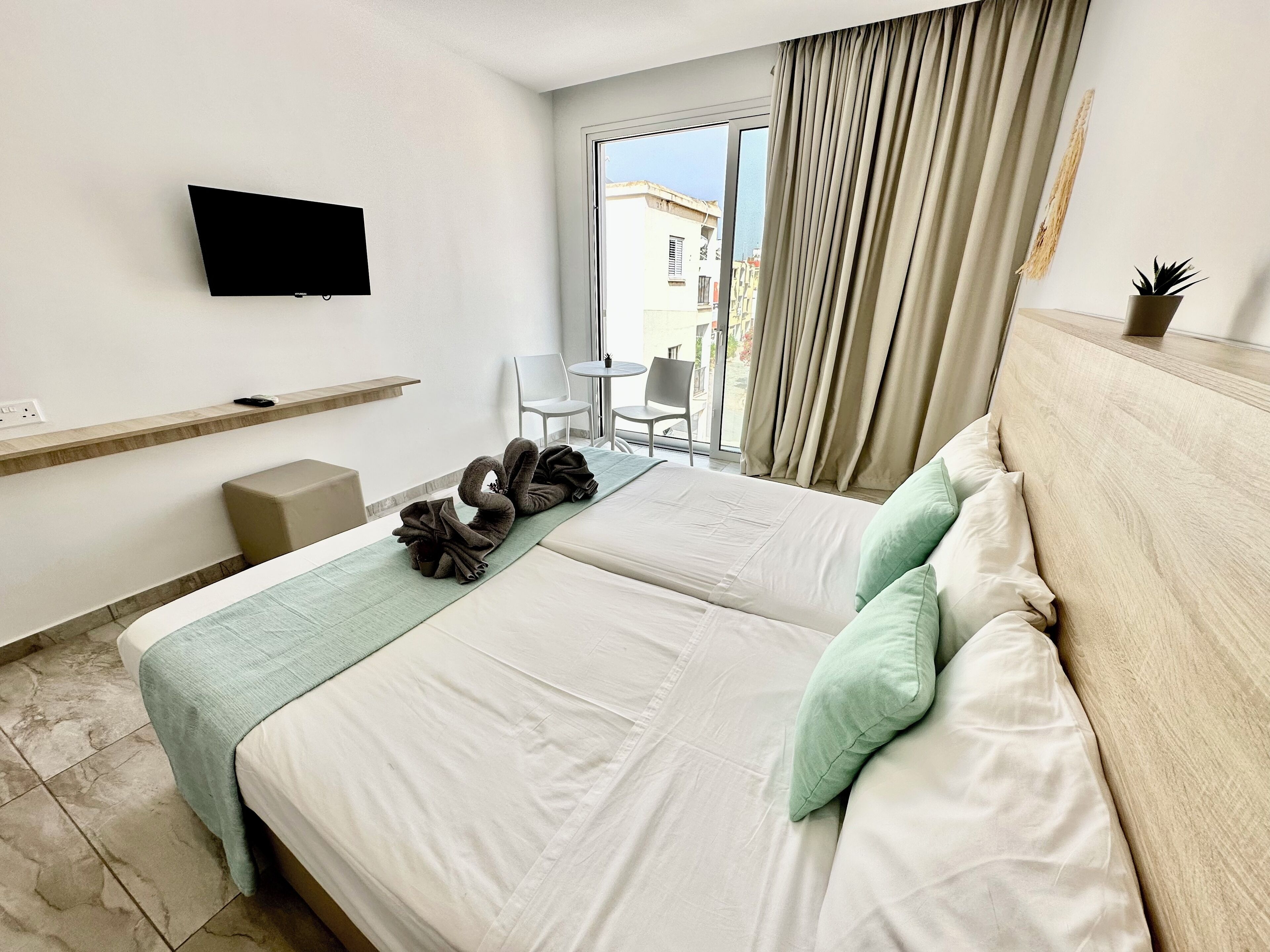 A hotel room with a bed, a TV, a small table, and a chair.