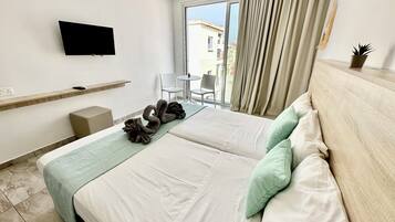 A hotel room with a bed, a TV, a small table, and a chair.