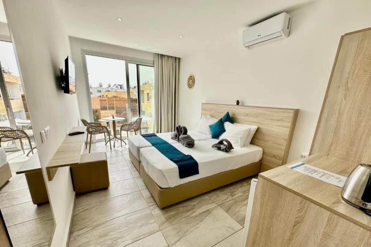 A hotel room with a bed, a desk, a chair, and a view of the city.