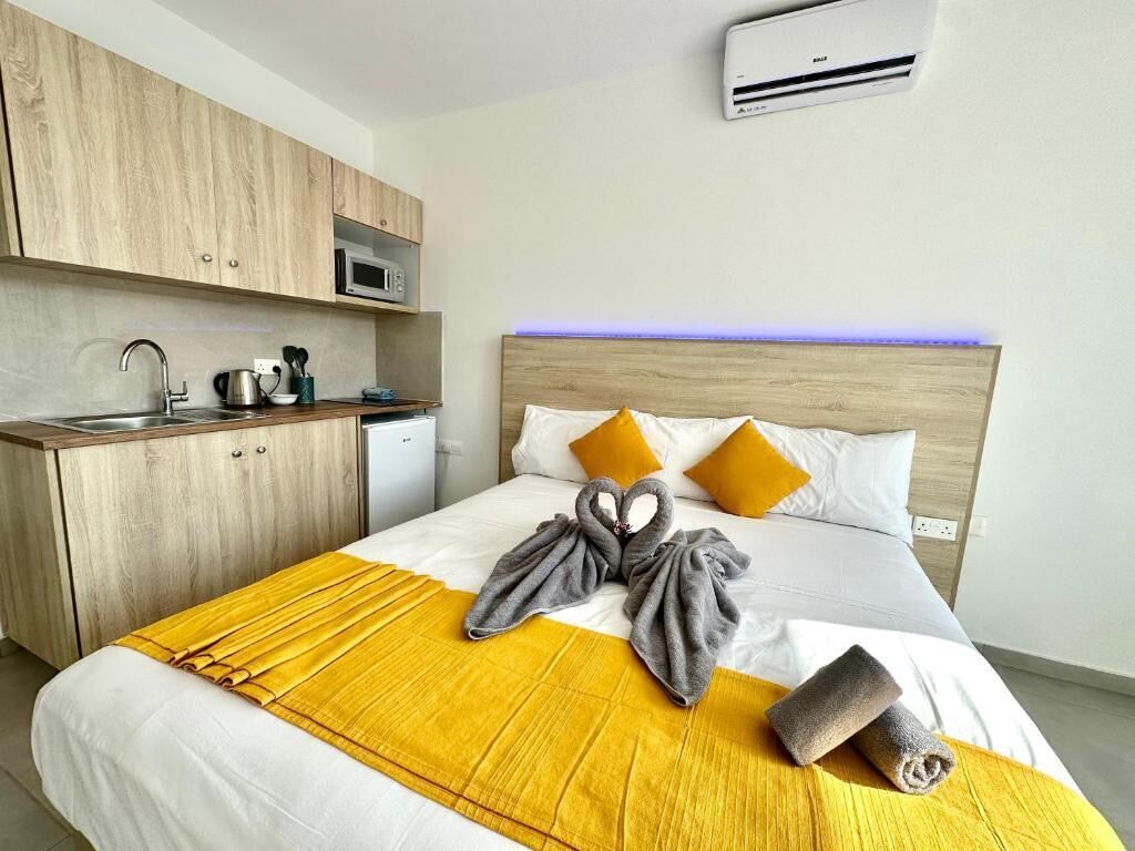 Una habitación de hotel con cama, armario de madera, microondas y lavamanos.
