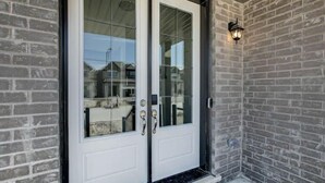 A double door with glass panels, a metal handle, and a small step leading up to it. - Sassafras Oasis | Sleeps 14 | All-Season Retreat Near Barrie (Minesing)