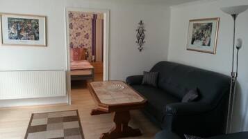Ein Wohnzimmer mit einem dunkelgrauen Sofa, einem Holztisch, einem gemusterten Teppich und einer Heizung.