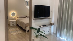 A modern bedroom with a bed, bedside table, and a mounted TV. - 5 minutes to the theme grand park. Pool view, spacious living room (Thành phố Hồ Chí Minh)
