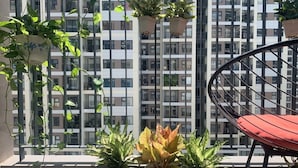 A balcony with potted plants, a chair, and a view of a high-rise building. - 5 minutes to the theme grand park. Pool view, spacious living room (Thành phố Hồ Chí Minh)