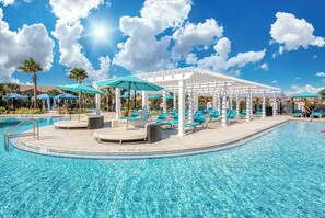 A swimming pool with lounge chairs and umbrellas, surrounded by a covered seating area. - "Windsor Haven" - Luxury Villa with Game Room (Kissimmee)