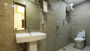 A modern bathroom with a sink, mirror, towel rack, handheld showerhead, and toilet. - Mehak Palace (Noida)