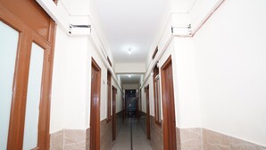 A corridor with wooden doors and marble flooring, leading to a staircase. - Mehak Palace (Noida)