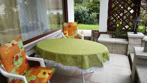 A patio with a round table and two chairs, covered with a green tablecloth.