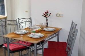A dining table set with plates, glasses, and a vase of flowers.