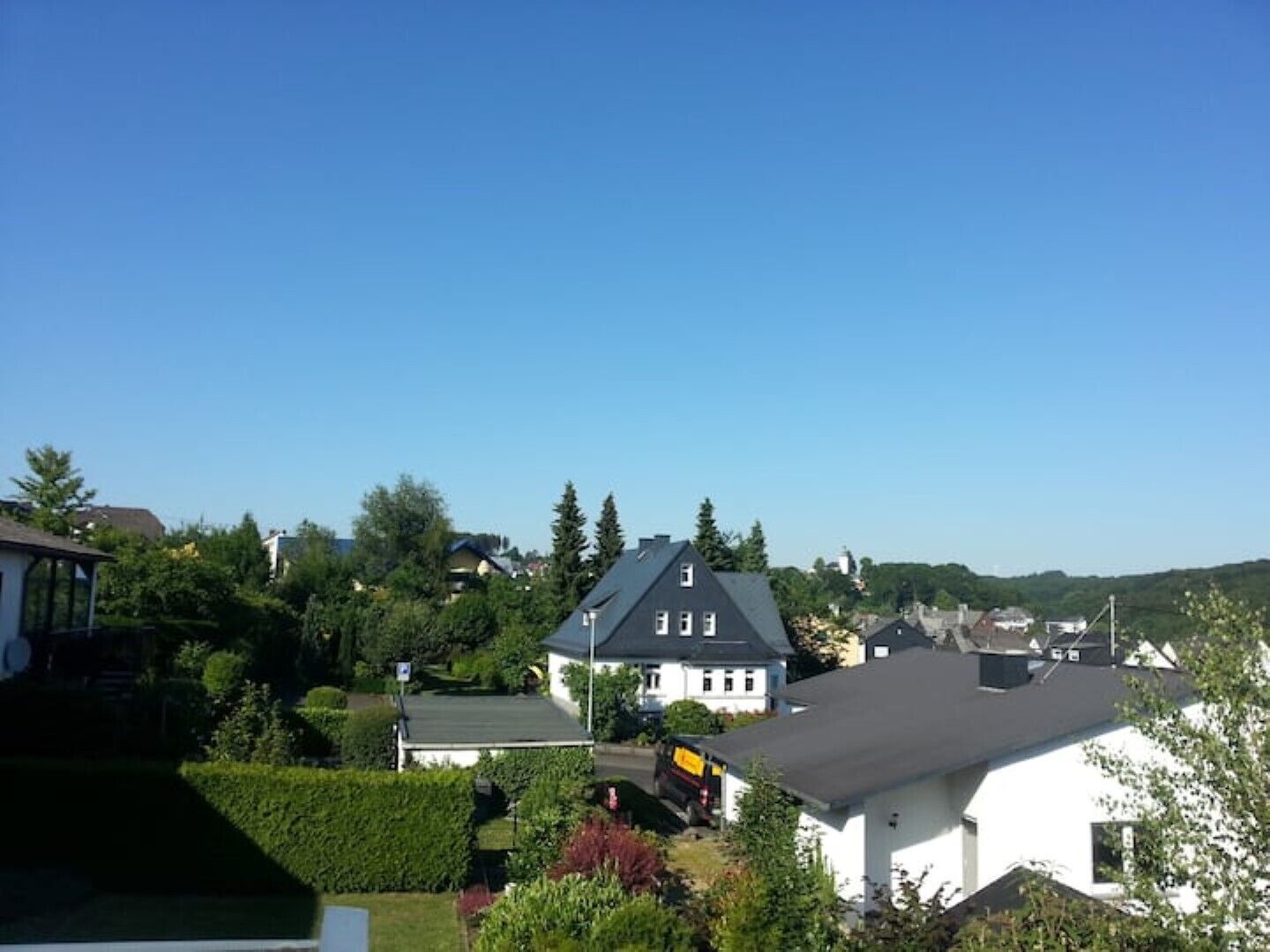 Asuinalue, jossa on taloja, kirkas taivas ja vehreää kasvillisuutta.