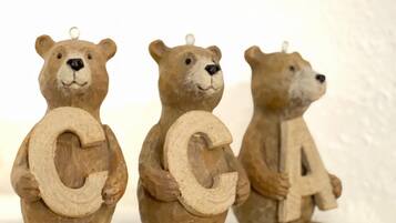 Tres figuras de madera de osos sosteniendo las letras C, C y A, sobre una estantería blanca.