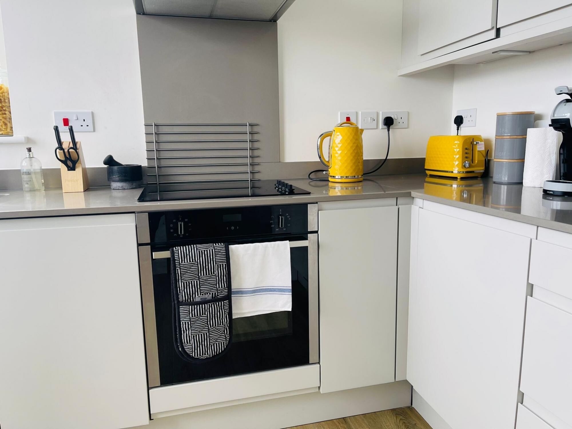 A modern kitchen with a built-in oven, a kettle, and a coffee machine.
