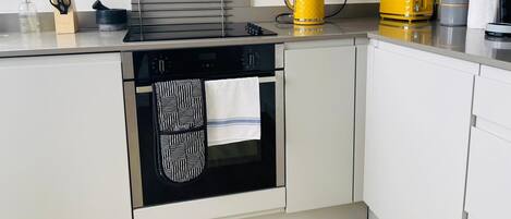 A modern kitchen with a built-in oven, a kettle, and a coffee machine.