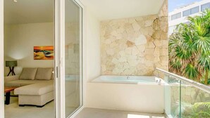 Een moderne badkamer met een stenen muur, een ligbad en een douche met glazen wanden.