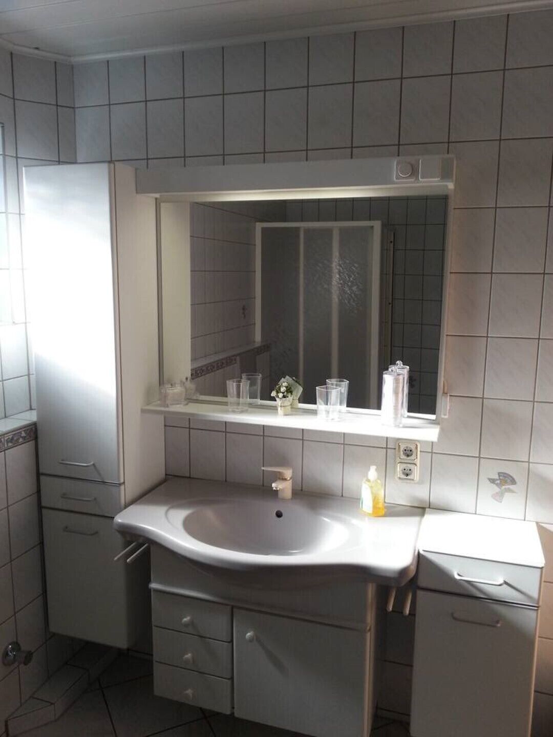 Un baño moderno con un espejo grande, un lavamanos y un armario.