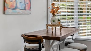 A dining area with a wooden table, four chairs, a chandelier, and a painting of guitars. - Burgess Falls bungalow minutes from Cookeville (Sparta)