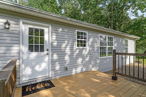 A single-story house with a front door, a small porch, and a wooden deck.