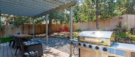 Une terrasse avec un barbecue, des sièges d’extérieur et une pergola.