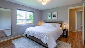 Ein Schlafzimmer mit Bett, Fenster, Spiegel und Tür.
