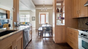 A kitchen with wooden cabinets, a granite countertop, a stainless steel dishwasher, and a built-in oven. - Rooftop Deck Walk to River Downtown Fire pit (Bend)