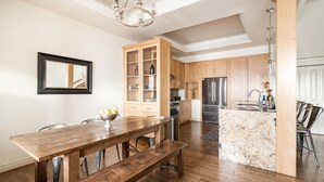 A modern kitchen with wooden cabinets, a built-in island, and a dining area with a wooden table and bench. - Rooftop Deck Walk to River Downtown Fire pit (Bend)