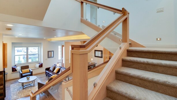 A modern interior with a wooden staircase leading to an upper level, a cozy living area with a sofa and coffee table, and a large window providing natural light. - Rooftop Deck Walk to River Downtown Fire pit (Bend)