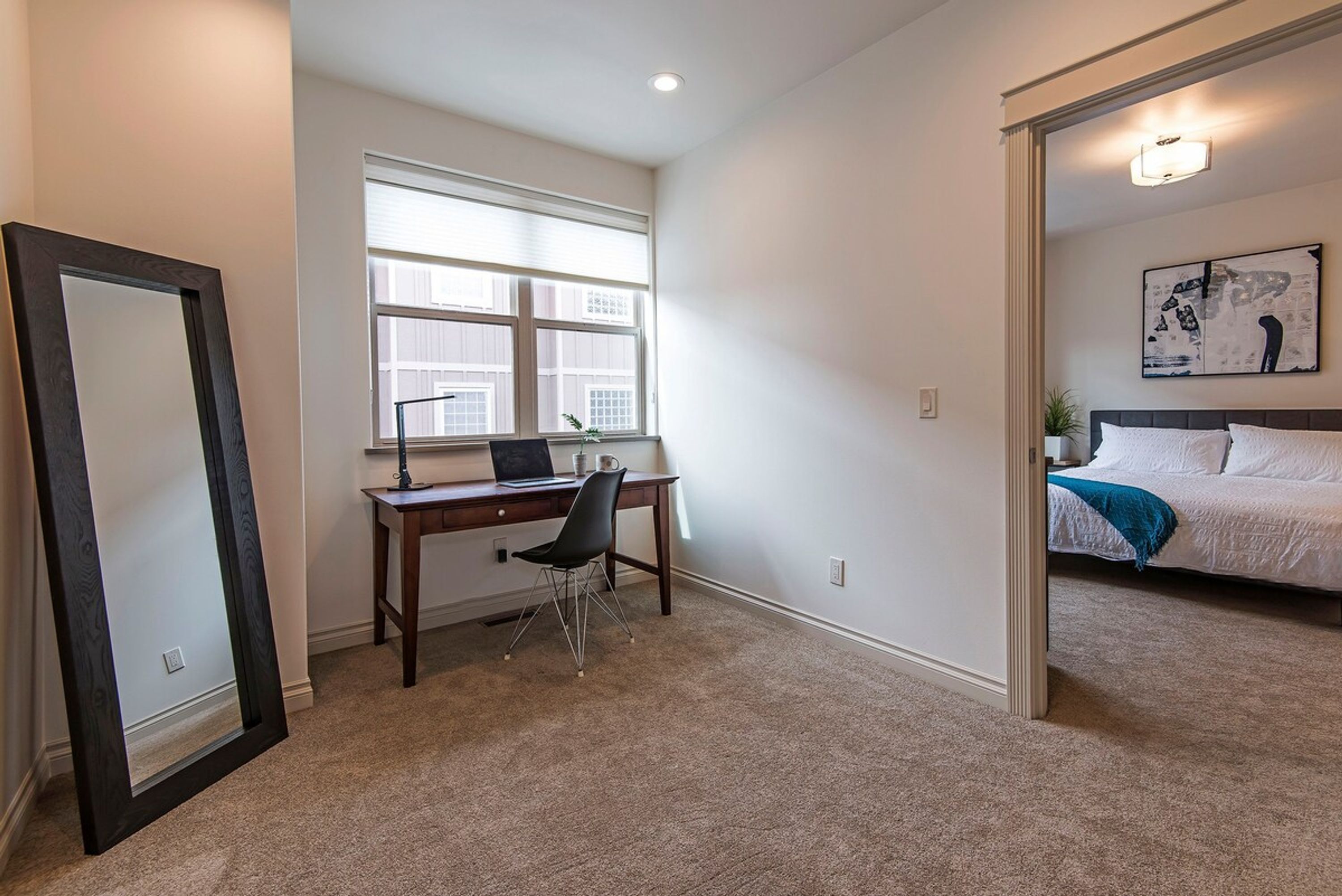 A bedroom with a bed, a desk, and a chair.