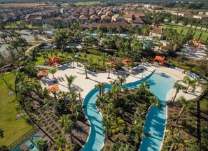 An aerial view of a resort with a large swimming pool, palm trees, and multiple buildings. - Gated Luxury Resort Home With South Facing Pool (Davenport)