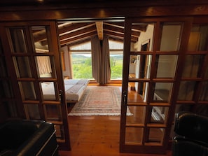 A bedroom with a large window, wooden floor, and a bed with a view of the outdoors. - High standard holiday villa in town close to Barcelona (Castellet)