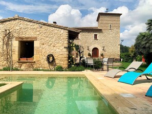 A stone building with a pool, outdoor seating, and a small tower. - High standard holiday villa in town close to Barcelona (Castellet)