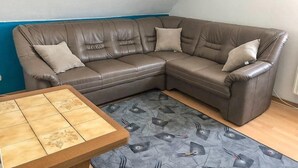 A corner living room with a brown leather sectional sofa, two pillows, and a small wooden table. - 2 Bedroom Apartment in Bad Marienberg (Westerwald) (Bad Marienberg (Westerwald))