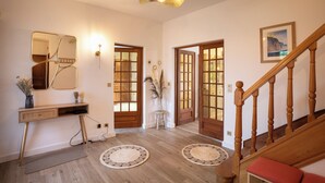 A spacious entryway with a wooden staircase, a console table with a vase, and a large mirror. - La Villa Maxine, sea view and spa (Criel-sur-Mer)