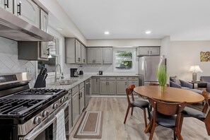 A modern kitchen with stainless steel appliances, grey cabinetry, and a dining area with a wooden table and chairs. - Valparaiso Corporate Home (Valparaiso)