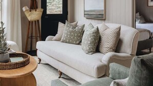 A cozy living room with a sofa, armchairs, a coffee table, and a hanging light fixture.