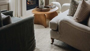 A cozy living room with a fireplace, a sofa, a coffee table, and a ceiling fan.