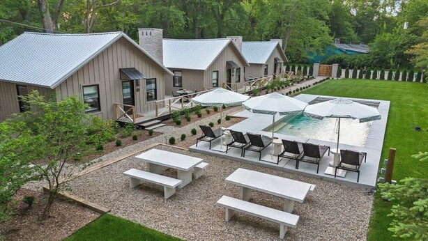 A modern outdoor patio with a pool, seating, and a small garden area.